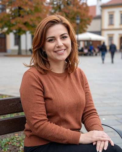 Mihaela, 32-year-old Moldovan woman from Ungheni with auburn hair sitting in a charming town square