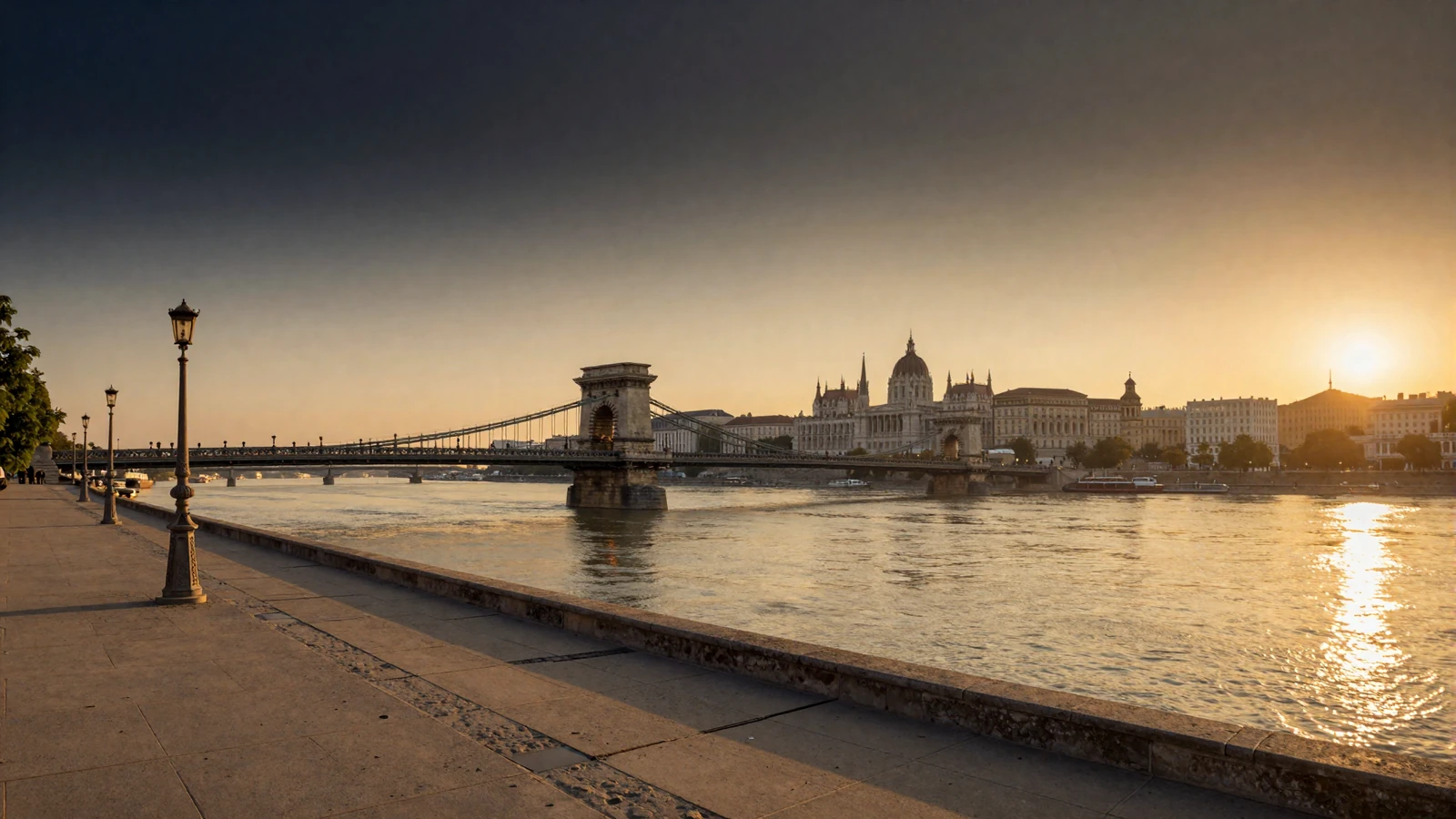 Budapest Danube riverfront at golden hour with Chain Bridge and Buda Castle glowing in warm amber light